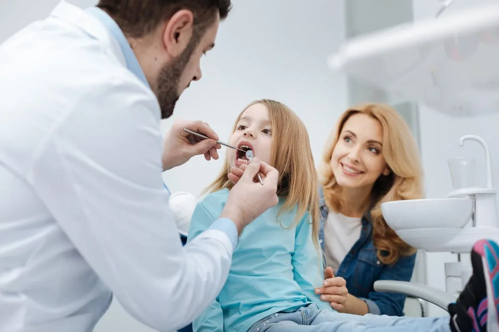 Photo of a dentist checking child's teeth