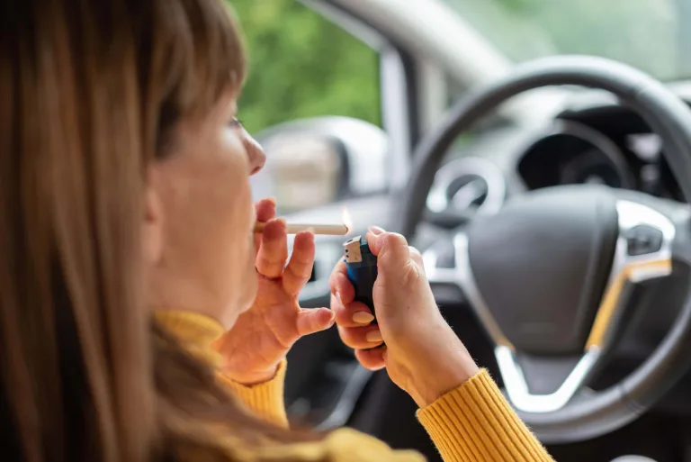 Woman lighting a cigarette in the car