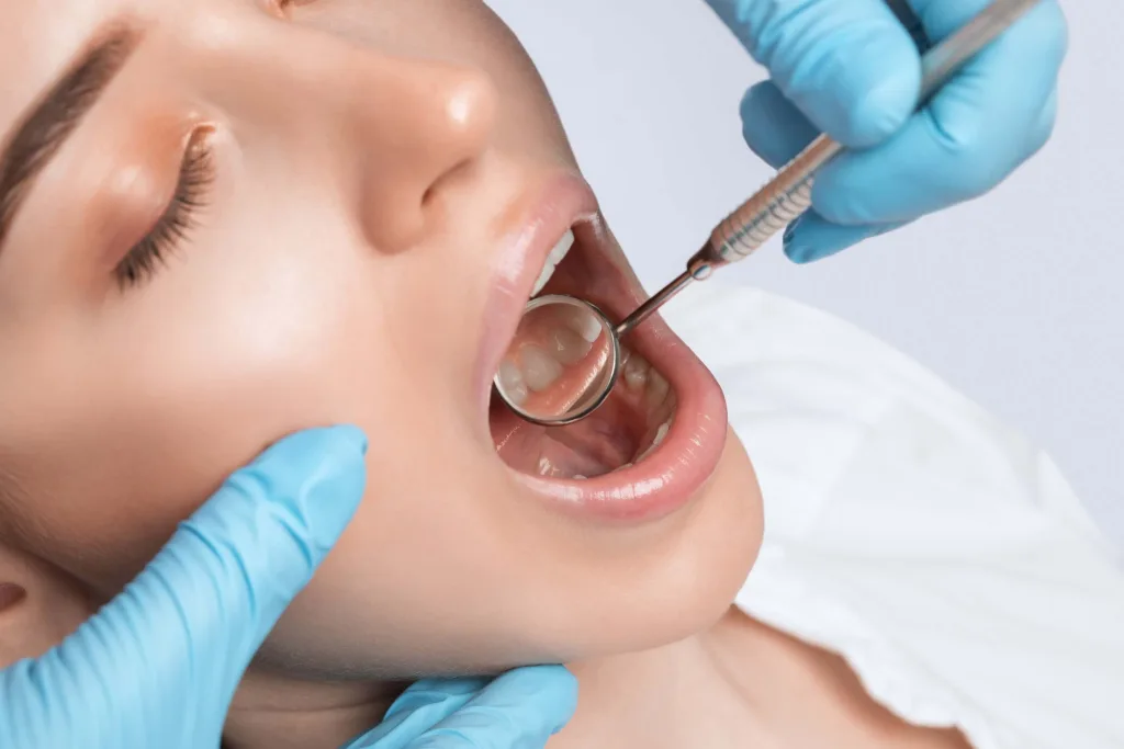 A dentist doctor treats cavities in a tooth of a young beautiful woman in a dental clinic