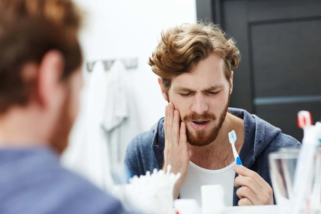 Man with sensitive teeth touching his cheek